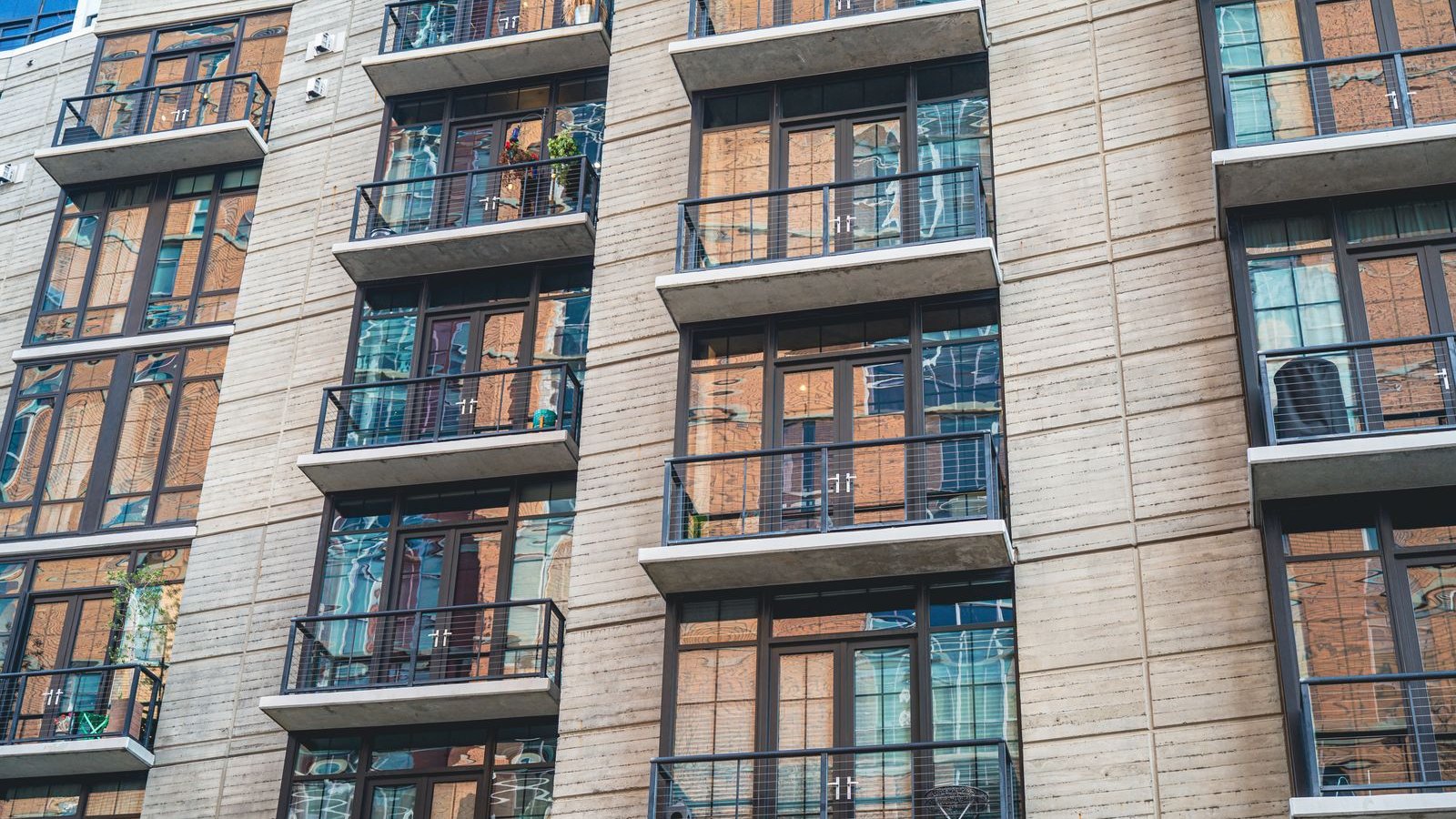 Façade d'un immeuble résidentiel moderne avec balcons vitrés, exemple de programme neuf en VEFA